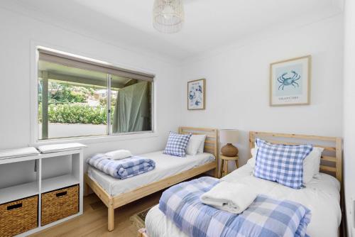 a bedroom with two beds and a window at Coast House Mollymook in Mollymook