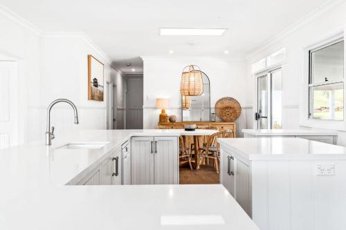 a white kitchen with white cabinets and a table at Woodstock Retreat Milton in Milton