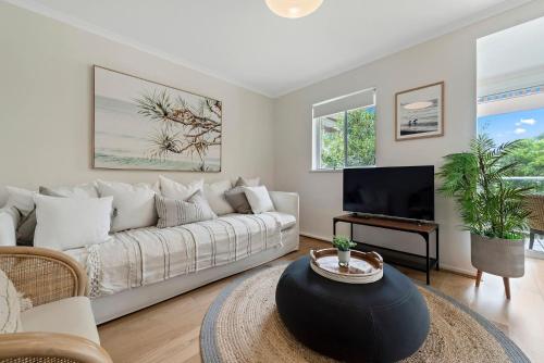 a living room with a white couch and a tv at Sandy Days in Mollymook Beach in Mollymook