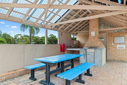 a patio with two blue picnic tables and a grill at Sandy Days in Mollymook Beach in Mollymook