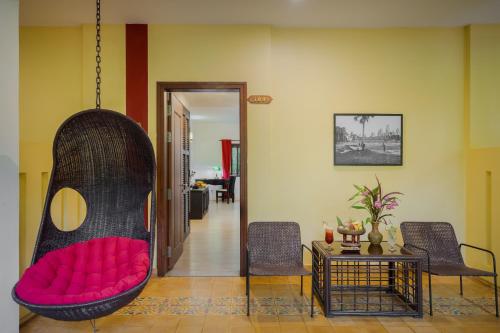 a room with a hanging chair with a red couch at Pandora Suite D'Angkor in Siem Reap