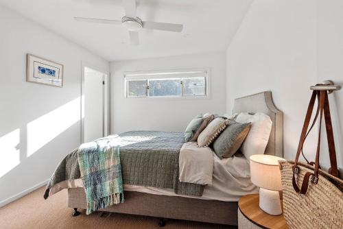 a white bedroom with a bed and a window at Breezeway Mollymook in Mollymook