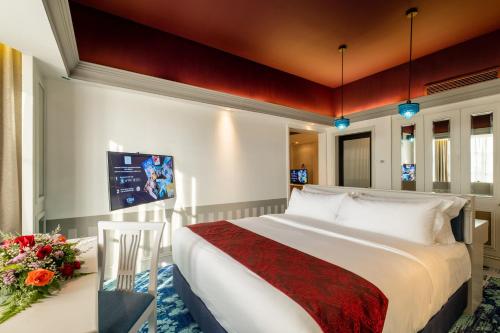 マラッカにあるGrand Swiss-Belhotel Melaka - formerly LaCrista Hotel Melakaのベッドと花のテーブルが備わるホテルルームです。