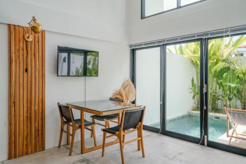 ein Esszimmer mit einem Tisch, Stühlen und einem Pool in der Unterkunft Canggu 2Plex Apartment in Canggu