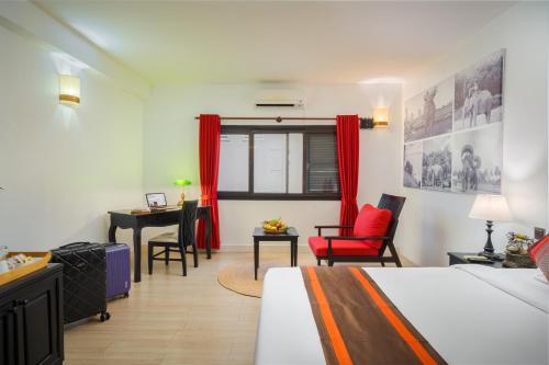 a bedroom with a bed and a desk and a table at Pandora Suite D'Angkor in Siem Reap