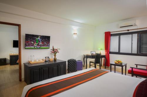a hotel room with a bed and a desk and a room at Pandora Suite D'Angkor in Siem Reap