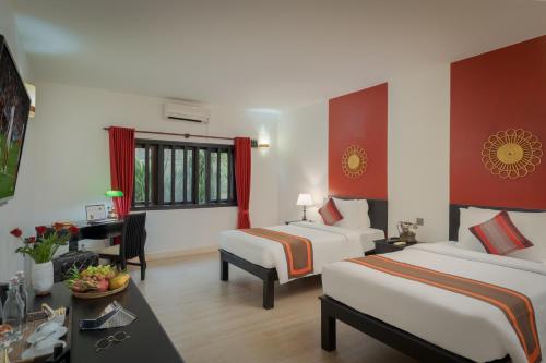 a hotel room with two beds and a desk at Pandora Suite D'Angkor in Siem Reap