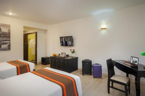 a hotel room with two beds and a desk at Pandora Suite D'Angkor in Siem Reap