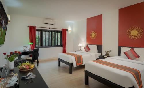 a hotel room with two beds and a desk at Pandora Suite D'Angkor in Siem Reap
