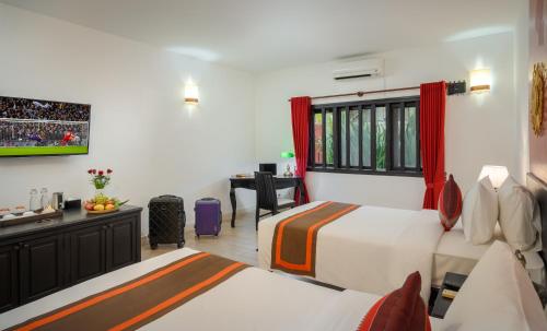 a hotel room with two beds and a desk at Pandora Suite D'Angkor in Siem Reap