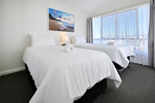 a hotel room with two beds and a window at Beachfront Choices - Beach, Lagoon, Spa ZE1 in Alexandra Headland