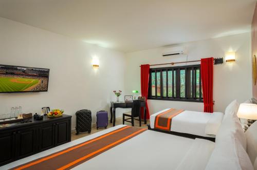 a bedroom with a bed and a desk and a television at Pandora Suite D'Angkor in Siem Reap