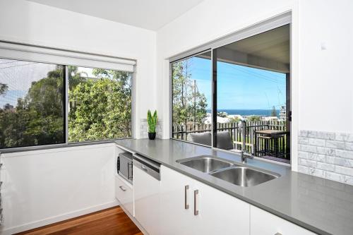 a kitchen with a sink and two large windows at Spacious New 2 bedroom Kings Beach Townhouse ZF2 in Caloundra