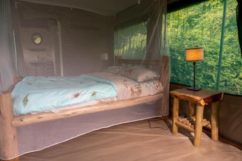 a bedroom with a bed and a table with a lamp at Greenwood safari camp in Talek