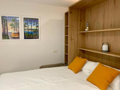 une chambre avec un lit avec des draps blancs et des oreillers jaunes dans l'établissement Studio à côté du lac avec terrasse, à Soorts-Hossegor