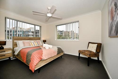 a bedroom with a bed and a chair and windows at Stylish 2 B/R Kings Beach Apartment (6 guests) ZF4 in Caloundra