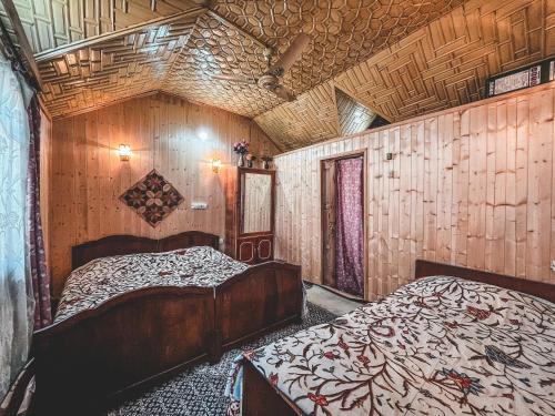 two beds in a room with wooden walls at Golden Hopes Group of Houseboats in Srinagar