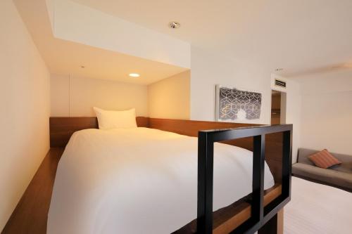 a bedroom with a bed and a couch at QuintessaHotel KagoshimaTenmonkan Relax&Sleep in Kagoshima