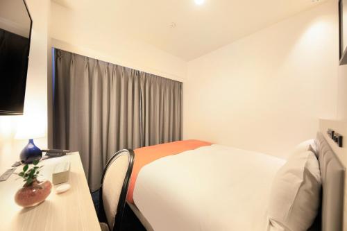 a hotel room with a bed and a table with a lamp at QuintessaHotel KagoshimaTenmonkan Relax&Sleep in Kagoshima