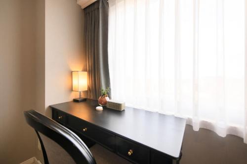 a desk with a lamp and a window at QuintessaHotel KagoshimaTenmonkan Relax&Sleep in Kagoshima