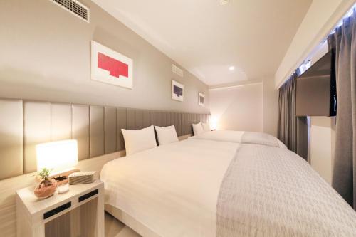 a bedroom with a large white bed and a television at QuintessaHotel KagoshimaTenmonkan Relax&Sleep in Kagoshima
