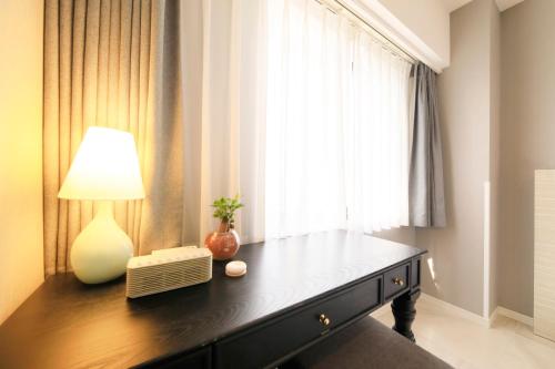 a room with a table with a lamp and a window at QuintessaHotel KagoshimaTenmonkan Relax&Sleep in Kagoshima