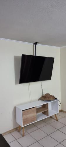 telewizor z płaskim ekranem na białej szafce w obiekcie Departamento Full equipado w mieście Santiago