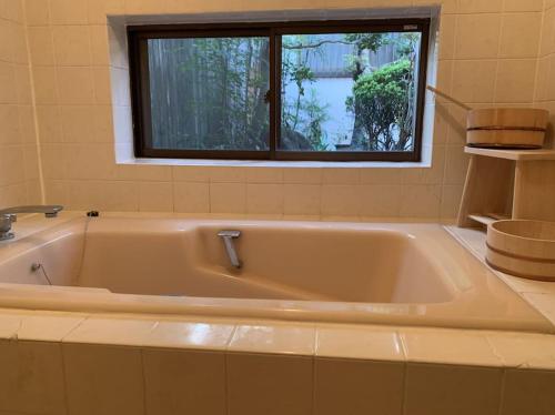 La salle de bains est pourvue d'une baignoire et d'une fenêtre. dans l'établissement Old Japanese House, à Tondabayashi