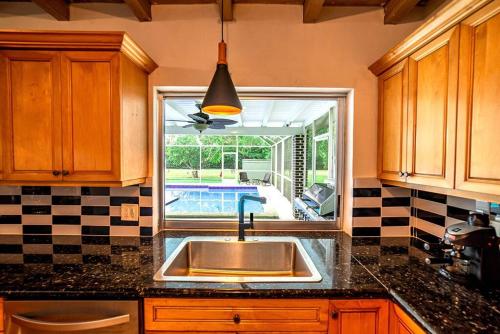 uma cozinha com um lavatório e vista para uma piscina em Luxury Miami Village w/Pool+Grill+MiniGolf em Miami
