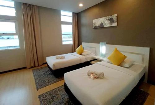 a hotel room with two beds with a stuffed animal on them at Lovita Hotel Kuantan in Kuantan