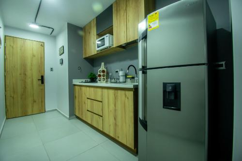 a kitchen with a stainless steel refrigerator and wooden cabinets at Barcelo Coliving in Medellín