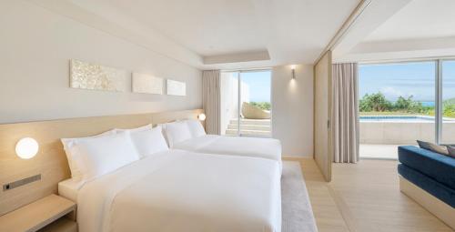 a bedroom with a white bed and a blue couch at IRAPH SUI, a Luxury Collection Hotel, Miyako Okinawa in Miyako Island