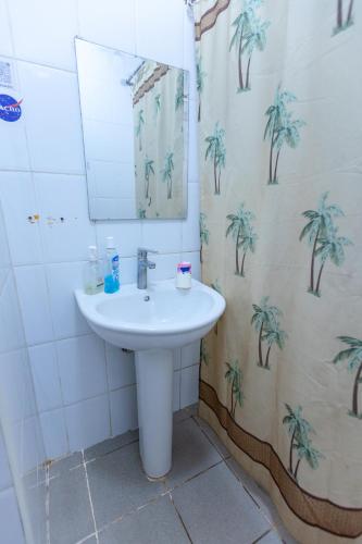 a bathroom with a sink and a shower curtain with palm trees at Acacia Villa Kampala in Kampala