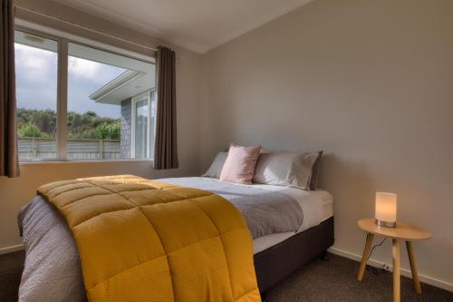 a bedroom with a bed with a yellow blanket and a window at Cambridge Modern 4 Bedrooms House in Cambridge