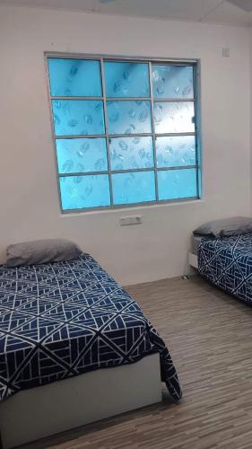 um quarto com 2 camas e uma janela em Garlic Cherating Pool Homestay em Kampong Baharu Cherating