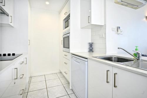 a white kitchen with white cabinets and a sink at Beachfront Choices Choices Choices in Alexandra Headland