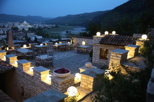 eine Terrasse mit Tischen und Stühlen in einem Gebäude mit Beleuchtung in der Unterkunft Hotel Vila Aleksander in Berat