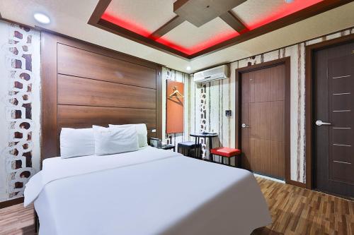 a bedroom with a large white bed with a wooden headboard at Picasso Motel in Seoul