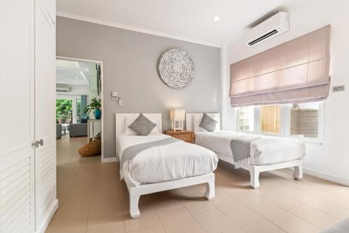 a white bedroom with two beds and a window at 2BR Villa Baan Orchid, seconds to beach in Lamai