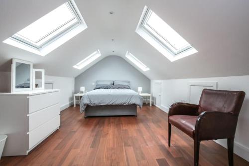 a bedroom with skylights and a bed and a chair at Large Modern Spacious House 6 Bedrooms 5 Bathrooms in London