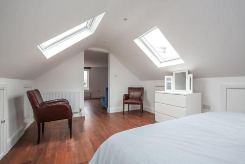 a bedroom with two chairs and a bed with skylights at Large Modern Spacious House 6 Bedrooms 5 Bathrooms in London