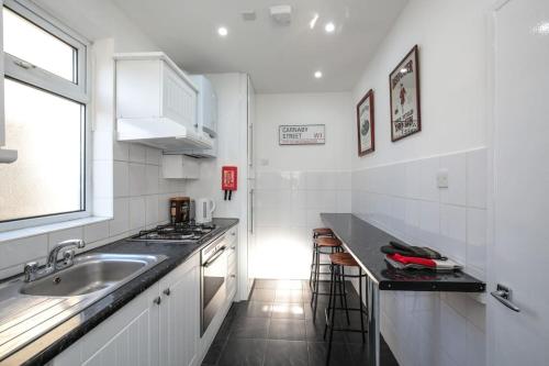 a white kitchen with a sink and a counter at Large Modern Spacious House 6 Bedrooms 5 Bathrooms in London
