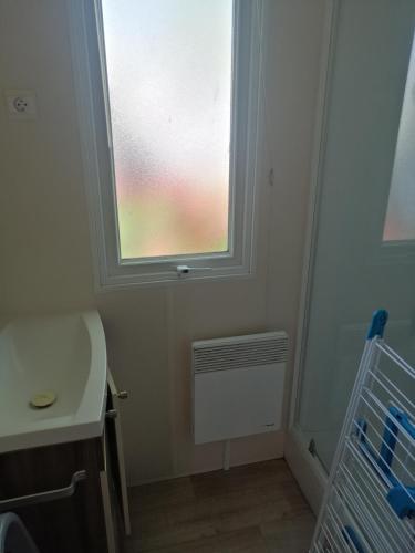 a bathroom with a window and a sink and a radiator at MHVACANCES LOUENT PLUSIEURS MOBILHOMES DANS CAMPING 4 ETOILES PROCHE CHATEAUX et ZOO BEAUVAL in Onzain