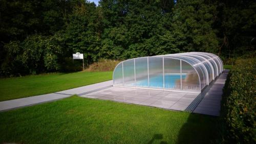 a swimming pool in a plastic greenhouse in a yard at Hotel Waldhaus in Römhild