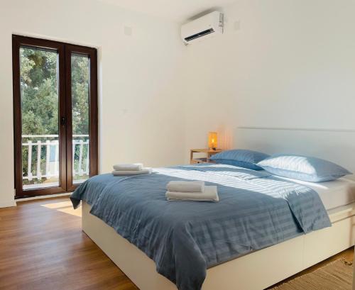 ブロダリツァにあるApartment Happyの青いシーツのベッドと窓のある寝室