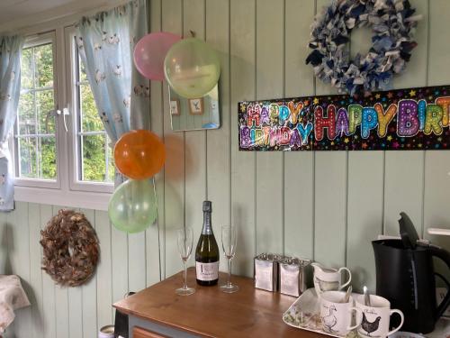 a table with two glasses of wine and balloons at Bells Meadow Shepherds Hut in Kings Lynn