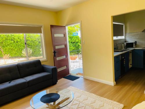 sala de estar con sofá, mesa y cocina en Heart of Katoomba Semi 1 bedroom home, en Katoomba