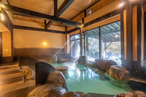 a pool of water in a room with rocks in it at Kusatsu Now Resort Hotel in Kusatsu