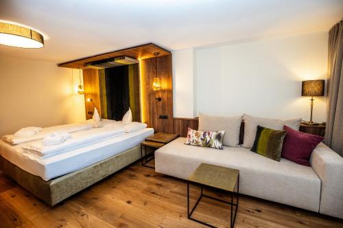 a hotel room with a bed and a couch at Moseralm Dolomiti Spa Resort in Nova Levante