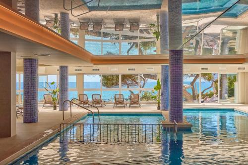 a pool in a hotel with a view of the ocean at Universal Hotel Lido Park & Spa in Paguera